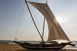 People In The Background Prints: View of Traditional Outrigger Fishing Boat (Oruva) with Sail on Negombo Beach, Sri Lanka