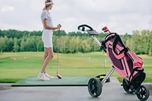 Spare Prints: side view of woman in polo and cap with golf club standing at golf course