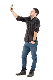 Full Body Prints: Side view of young casual man in jeans and shirt taking selfie with cellphone