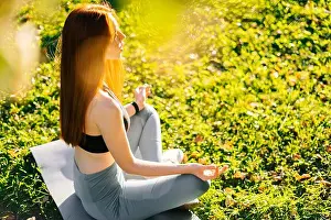 Practicing Prints: Side view of young red-haired woman with closed eyes meditating in lotus pose holding hands on knee