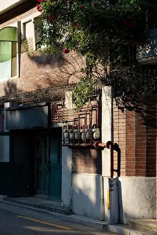 Korea Prints: Vintage Korean alleyway with an old red brick wall and gas meters bathed in warm sunlight