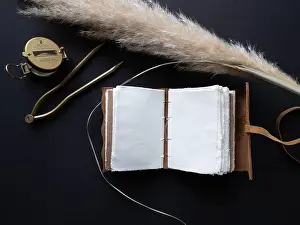 Compass Prints: Vintage leather journal or diary on a black table with a compass next to it
