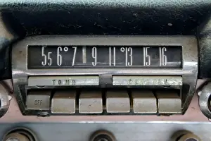 Manufacturer Prints: A vintage old AM push button car radio dial in chrome mounted in a dashboard
