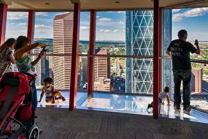 Group Of Prints: Visitors looking at downtown, standing on glass floor at Calgary Tower