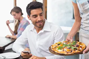 Waitress giving pizza to man at coffee shop