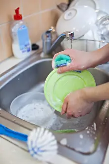 Cleanliness Prints: Washing of the dishes - woman hands rinsing dishes under running water in the sink