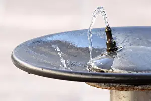 Plumbing Prints: Water flowing from a faucet in a public fountain and falling into a plate
