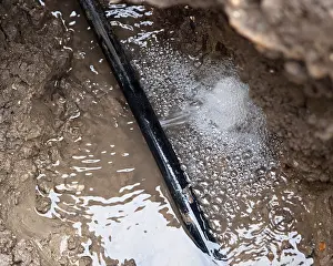 Split Prints: water leak in a polythene pipe underground in a trench before repairing