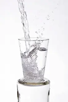Tasting Prints: Water vigorously poured overflowing splashing from a glass, on a white background