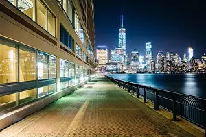 New York New York Prints: Waterfront walkway and view of the Lower Manhattan skyline at night
