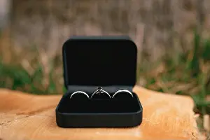 Blurred Background Prints: Wedding rings in white gold and an engagement ring in a black velvet box on a wooden base