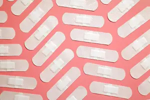 Sticking Prints: Many white adhesive band aids arranged on pink background