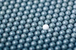 Goblet Prints: White airsoft ball is among many black balls. Background of 6mm bbs