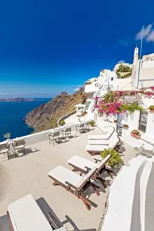 White architecture on Santorini island, Greece. Beautiful landscape with sea view. Chairs with flowers, romantic terrace sea view. Luxury travel