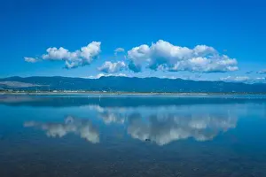 Stillness Prints: White cumulus clouds are reflected on the calm blue surface of the Missolonghi salt marsh in western Greece