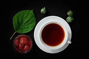Dark Background Prints: White cup with tea, strawberry jam