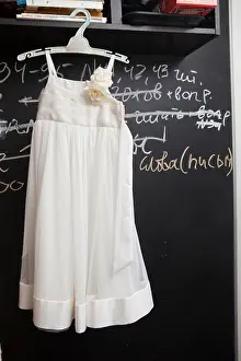 Gown Prints: white girl`s dress hangs near wall