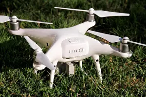 Remote Control Prints: White quadcopter Drone with 4K digital camera on grass is ready for take off to fly in air to take photos