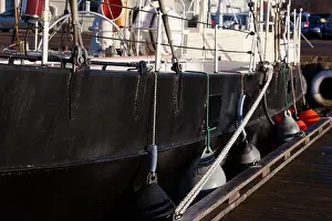 Tied Prints: A white rope holds the black sailing ship in place at the docks