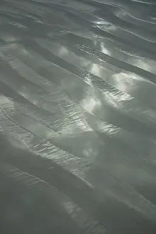 Rippling Prints: White sand ripples at the beach on a cloudy day