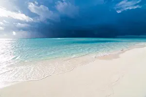 White tropical beach in Maldives with blue lagoon and a tropical storm