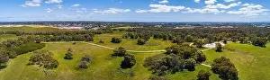 Travel Locations Prints: Wide aerial panoramic landscape of path winding through park with green grass and trees