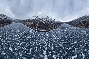 Wide angle drone view of frozen lake surrounded by snowy mountains under cloudy gloomy sky in Vatnajokull National Park