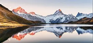 Wide panorama of Bachalpsee lake in Swiss Alps mountains. Snowy peaks of Wetterhorn, Mittelhorn and Rosenhorn on background