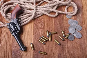 Cartridge Prints: Wild west gun, ammunition and silver dollars on wooden table