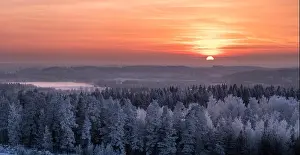 Winter landscape with frosty trees and beautiful sunset at evening time in Finland