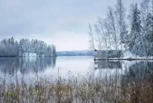 Winter landscape with sauna cottage and peaceful lake at evening in Finland