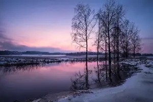 Winter landscape with sunset and smooth river at evening in Finland