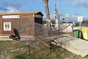 Rusty Prints: A wire sculpture of a fish sits on display near a first aid station and recycling bins