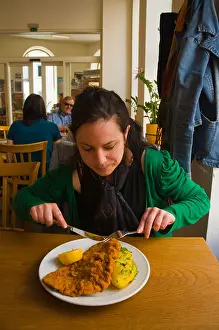 Osterreich Prints: Woman in her 20s having Wiener Schnitzel the breaded veal escalope in Schöne Perle restaurant interior Leopoldstadt