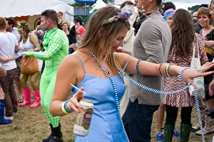 A woman with a can of beer and a cigarette dances in a field to a mobile sound system at the Standon Calling Festival