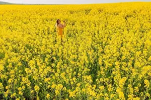 Trending Prints: Woman at blooming rapeseed field. Yellow flowers and happy woman