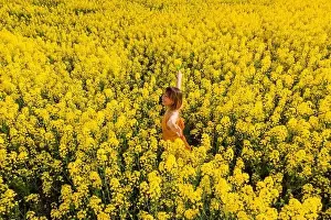 Trending Prints: Woman in blooming rapeseed field. Yellow flowers and happy woman
