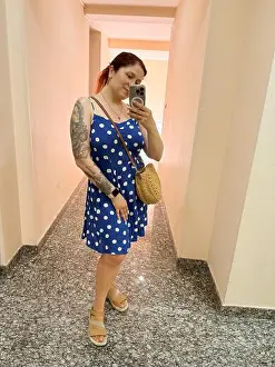 Polka Dot Prints: Woman in blue polka dot dress taking selfie in elevator mirror with round straw bag