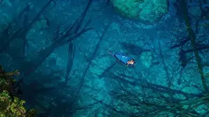 Woman on boat floating in most transparent lake with crystal blue fresh water in Sulawesi, Indonesia. Aerial view