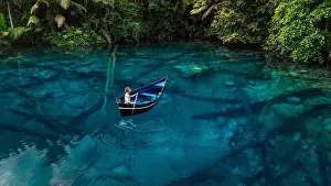 Woman on boat in tropical transparent lake with crystal blue water in Sulawesi, Indonesia. Aerial view