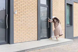 Pull Prints: woman in a coat and hat tries to open a closed door, pulls the door by the handle