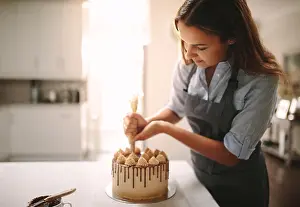 Baker Prints: Woman decorating chocolate cake in the kitchen. Female chef making a cake at home