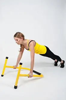 Bodybuilding Prints: Woman doing exercises with high yellow floor bars on a white background