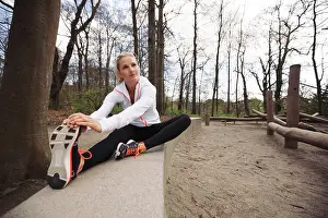 Flexibility Prints: Woman doing stretching exercise in park. Caucasian female model exercising in nature