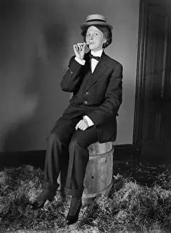 One Woman Prints: A woman dressed as man poses with an unlit cigarette in her mouth, ca. 1910