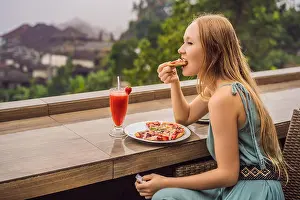 Pizza Prints: Woman eating delicious strawberry pizza on a balinese tropical nature background