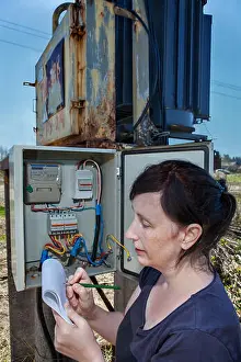 Meter Prints: Woman electrician engineer inspecting electric counter equipment in distribution fuse box