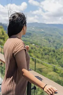 Mindfulness Prints: A woman enjoying a beautiful mountain view from a balcony while the wind blows her hair under bright daylight
