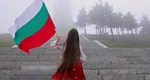 Bulgarian Prints: Woman in ethnic folklore costume with Bulgarian flag climbing Shipka monument