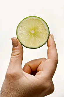 Presents Prints: Woman hand holding up a wedge of lime, isolated on white